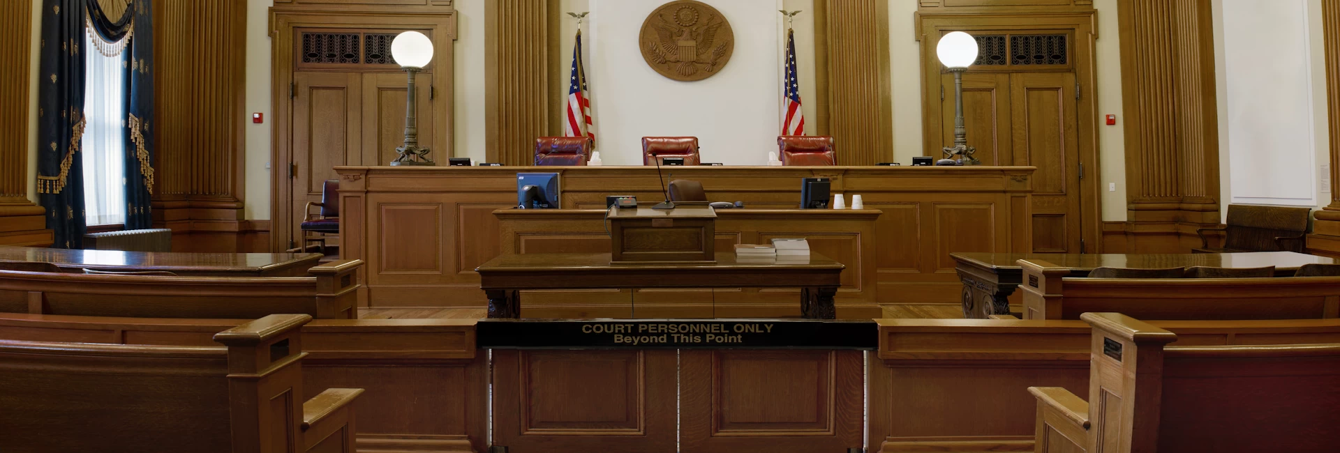 Federal Court of Appeals Courtroom facing bench, with two American Flags and eagle emblem. With the title Attorney written on top.